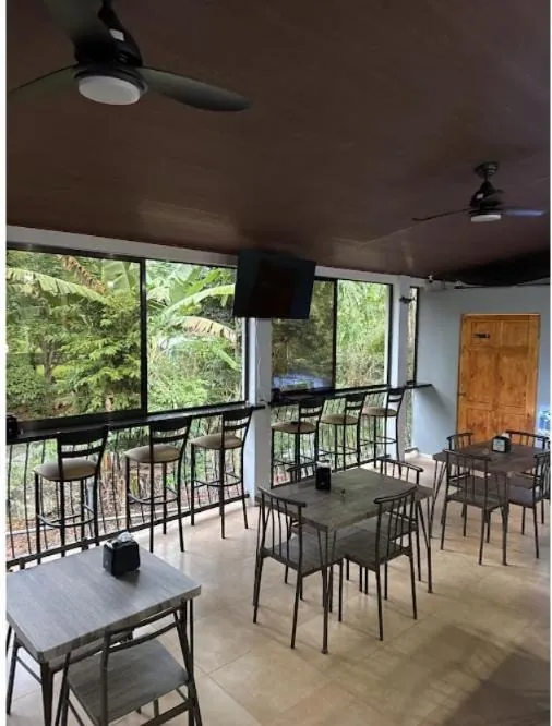 Salón de Boat House con ventanales hacia la vegetación, mesas y barra con bancos altos